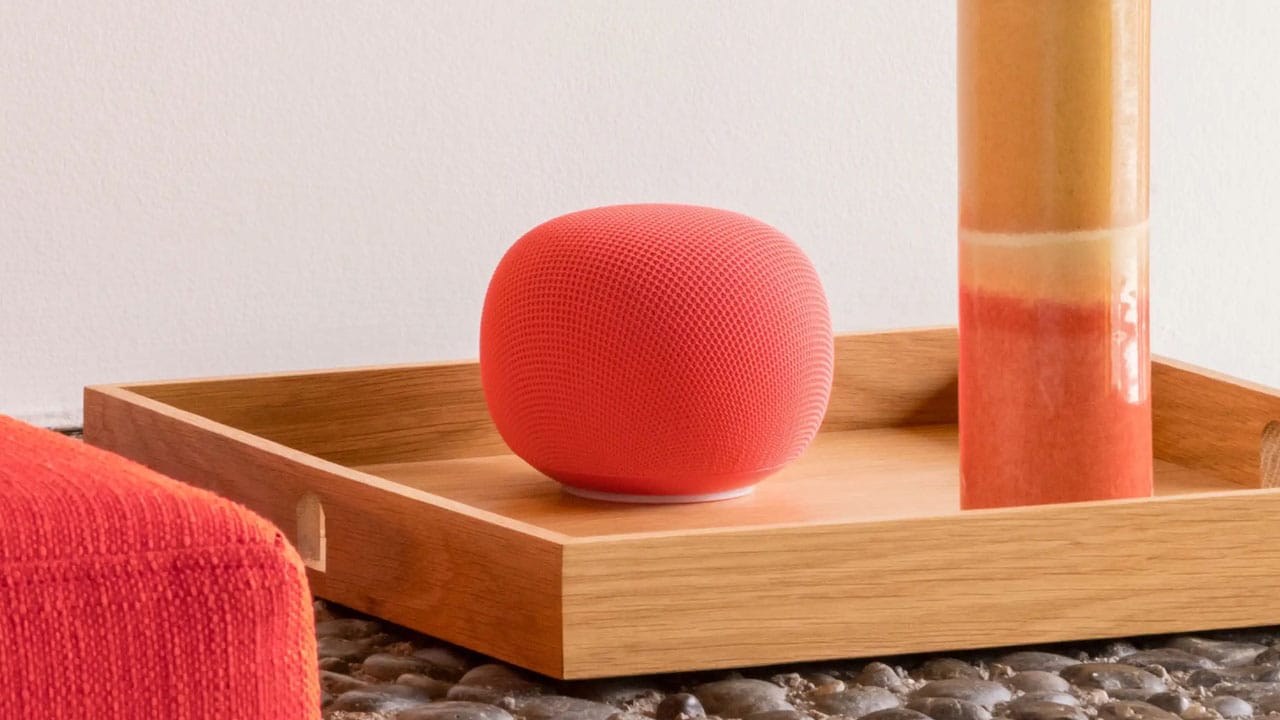 Google Home Speaker dalam balutan warna Hazel yang hangat, diletakkan di rak kayu bersama buku dan tanaman kecil
