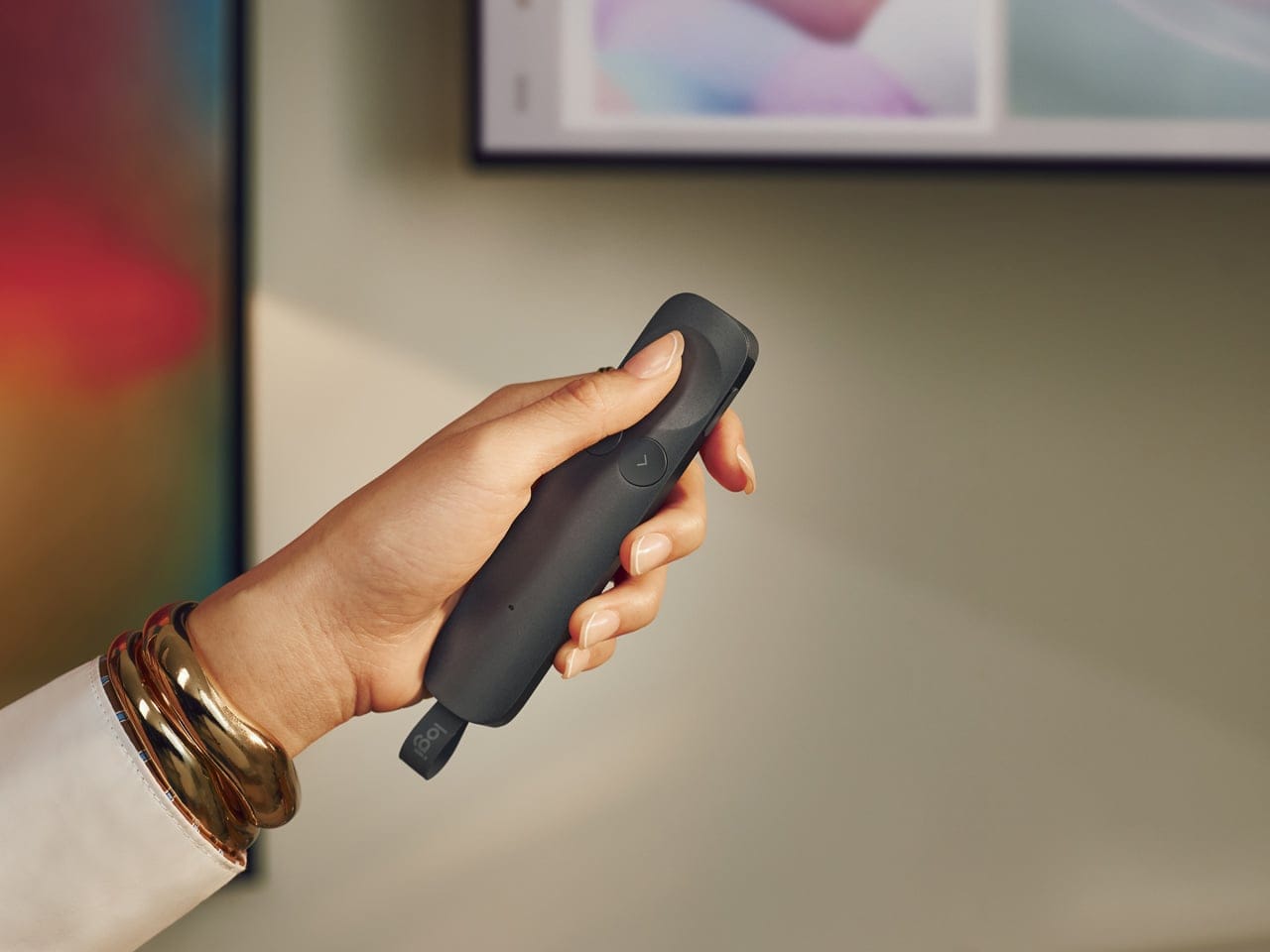 Remote presentasi Logitech Spotlight 2 berwarna emas pasir diletakkan di atas meja kerja kayu minimalis